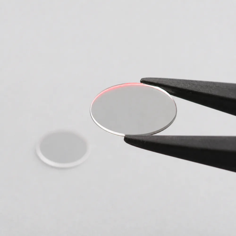Commonlands IR bandpass filter held in tweezers, its interference coating reflecting color