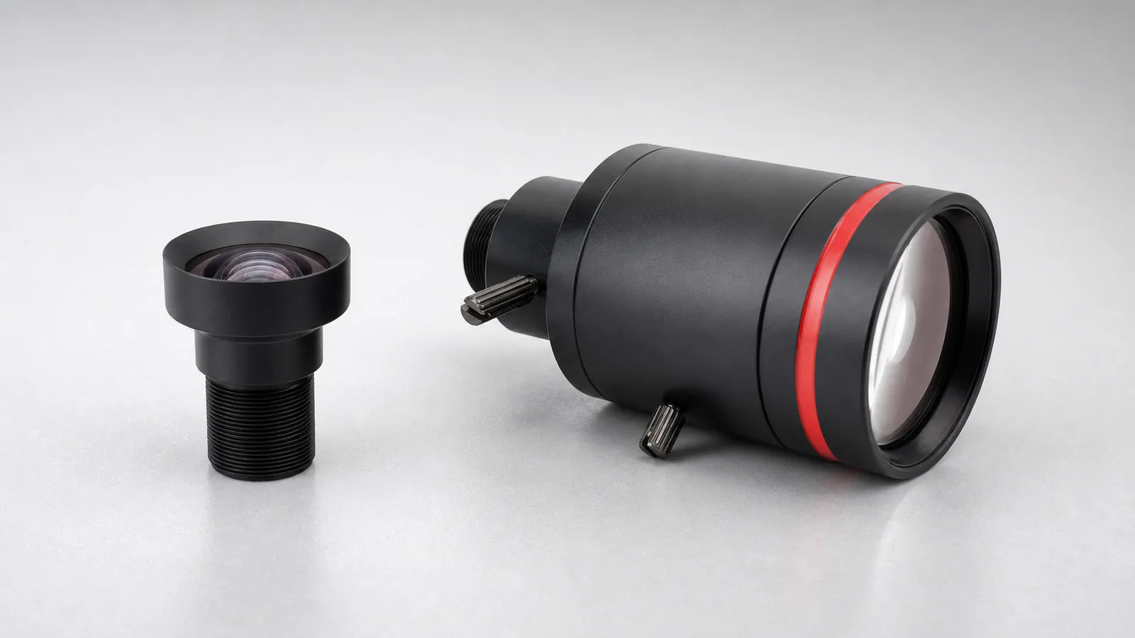Commonlands fixed focal length lens beside a larger varifocal lens with two adjustment rings