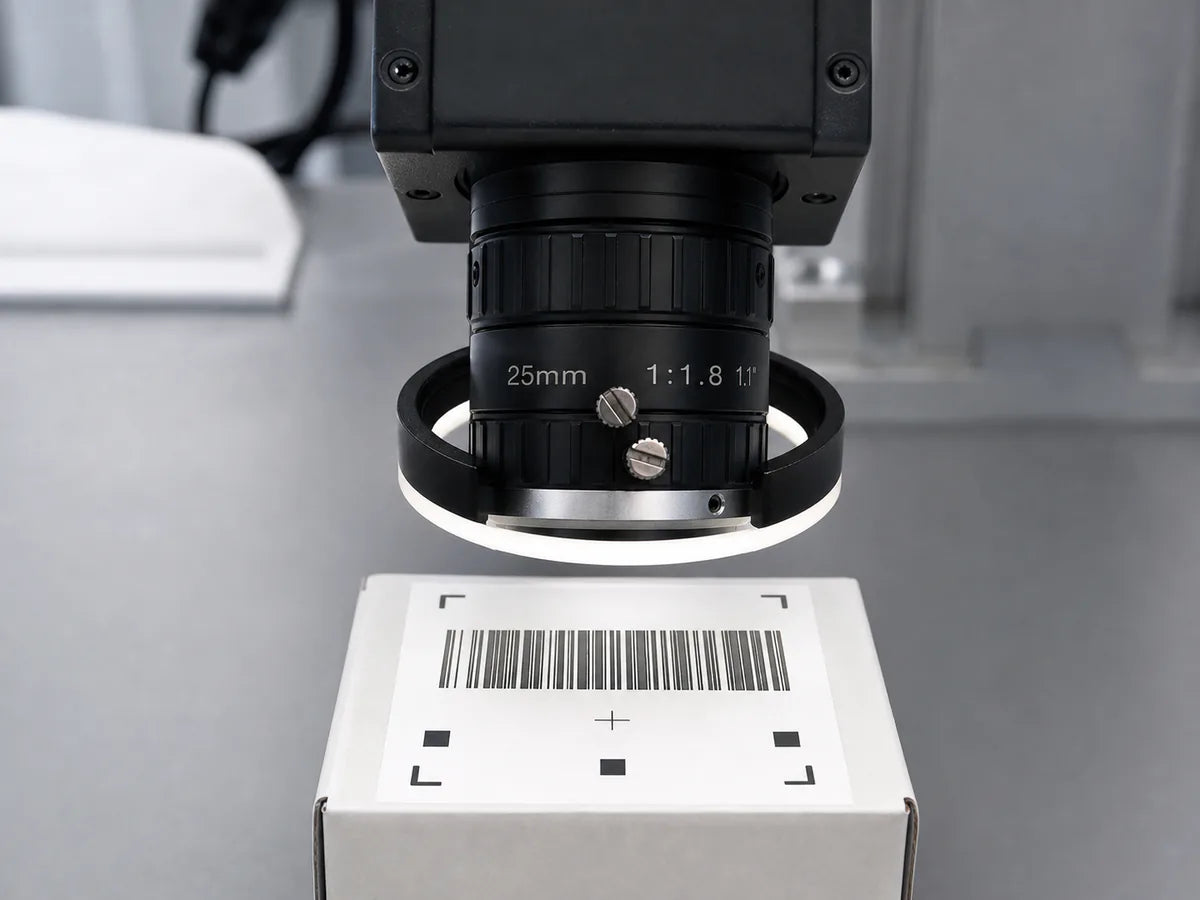 A machine vision camera and ring light reading a printed label on a package