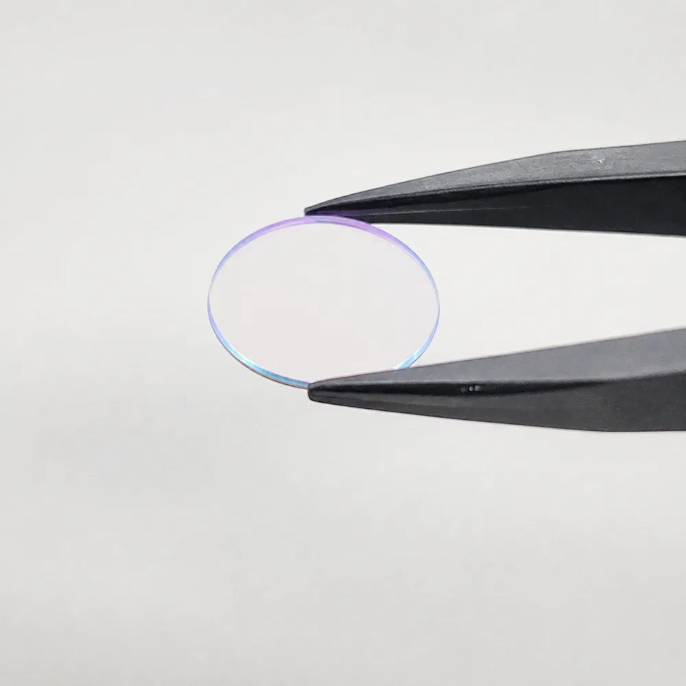 A Commonlands 850nm bandpass filter held in tweezers, its coating showing a dichroic color sheen