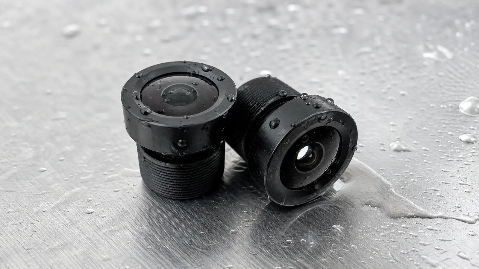 A ruggedized Commonlands all-metal M12 lens shedding water beads from its hydrophobic front coating