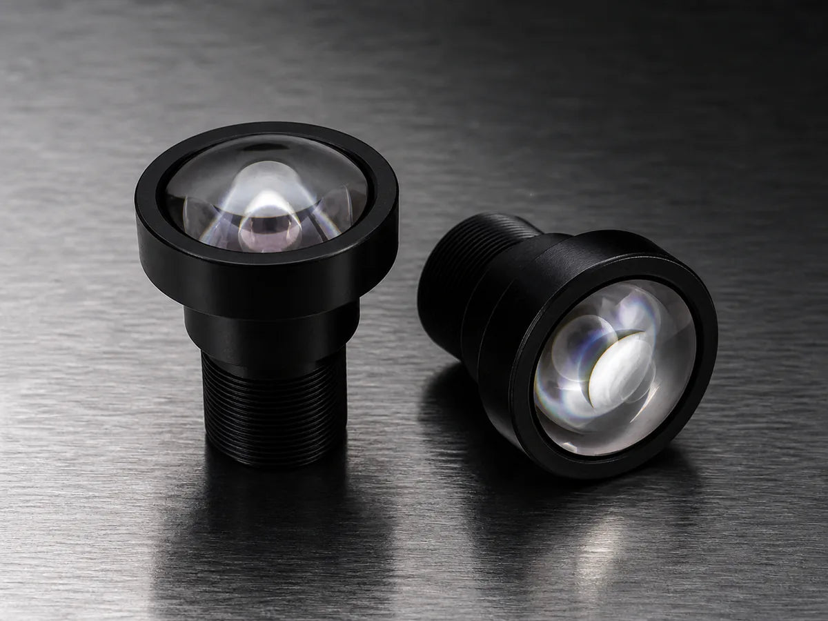 A large-front telecentric lens above machined parts silhouetted on a backlit gauging stage